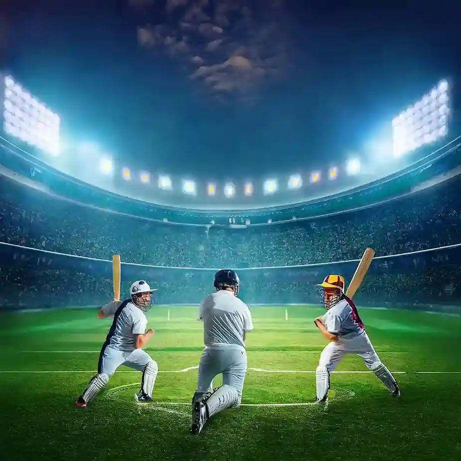 Three cricket players in helmets and whites poised on the pitch of a floodlit stadium